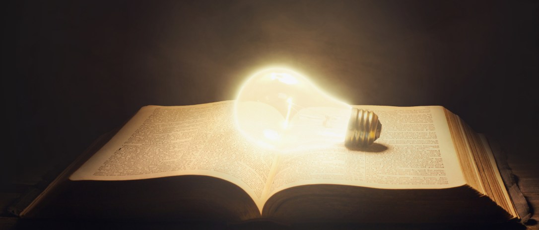 Surreal image of a glowing light bulb in an open Bible.